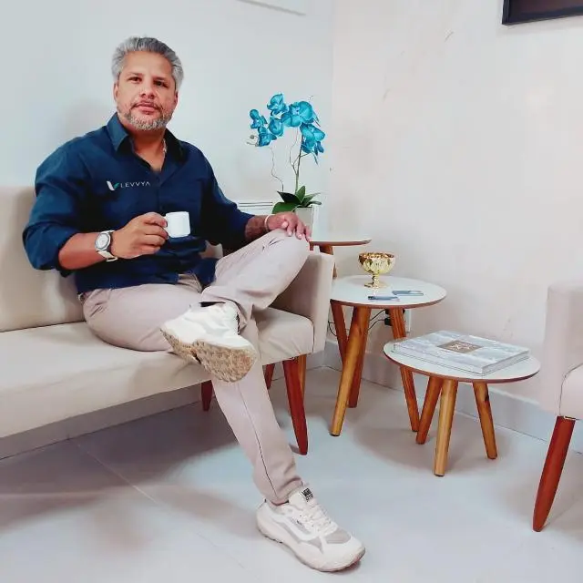Thiago, da LEVVYA, sentado no sofá do escritório com uma xícara de café